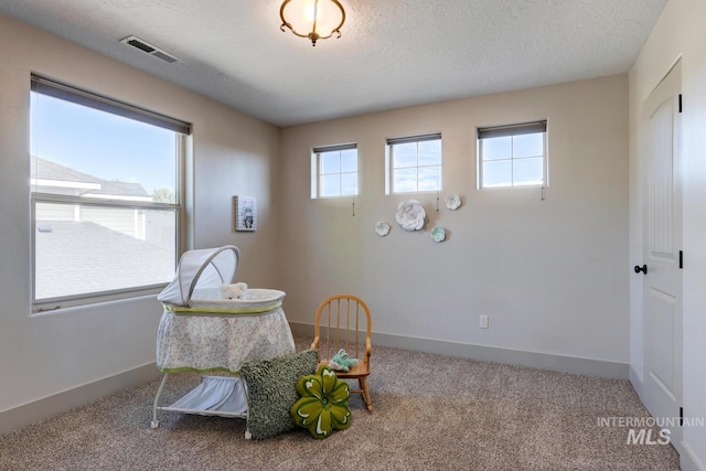 sitting room with baseboards, visible vents, a textured ceiling, and carpet