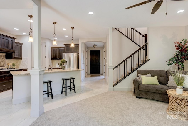 kitchen featuring light carpet, dark brown cabinets, arched walkways, and stainless steel appliances