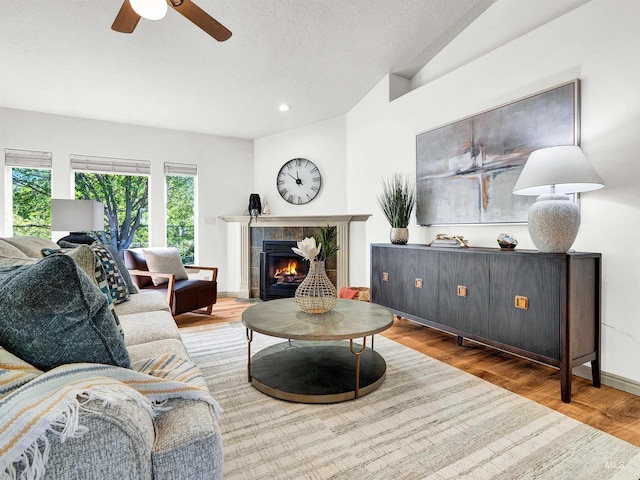 living area featuring wood finished floors, a ceiling fan, a tile fireplace, recessed lighting, and baseboards