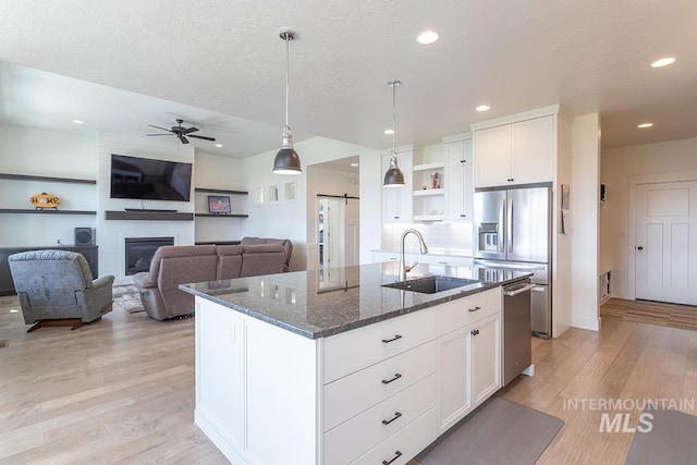 3713 W Ladle Rapids St, Meridian, ID 83646 - kitchen featuring a sink, open shelves, stainless steel appliances, dark stone counters, and light wood-type flooring