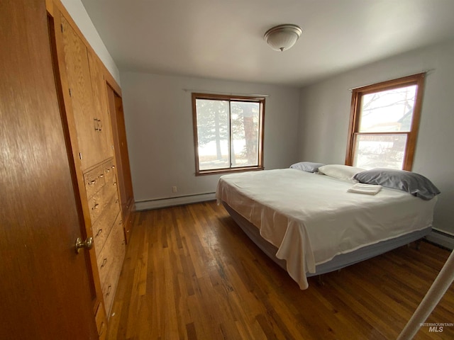 bedroom with a baseboard radiator, dark hardwood / wood-style floors, and a closet