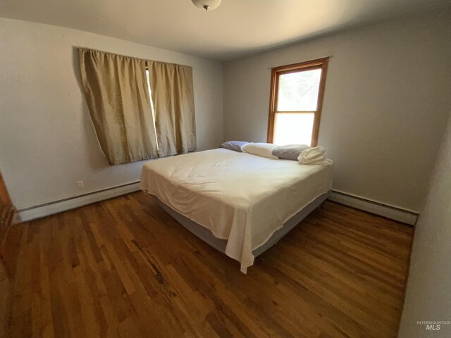 bedroom with dark wood-type flooring and a baseboard radiator