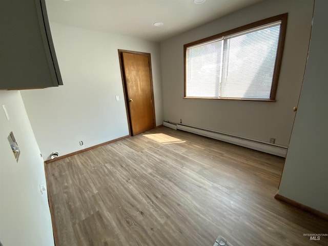 unfurnished bedroom featuring baseboard heating and light hardwood / wood-style floors