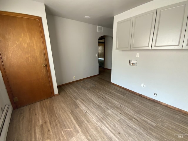 empty room with a baseboard heating unit and light hardwood / wood-style floors