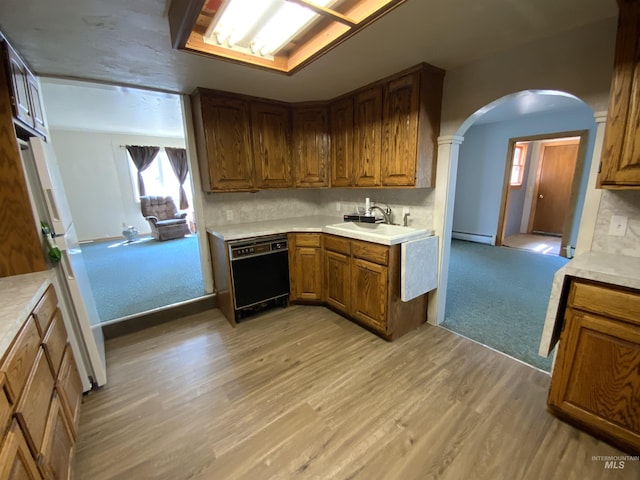 kitchen with dishwasher, sink, backsplash, light colored carpet, and baseboard heating