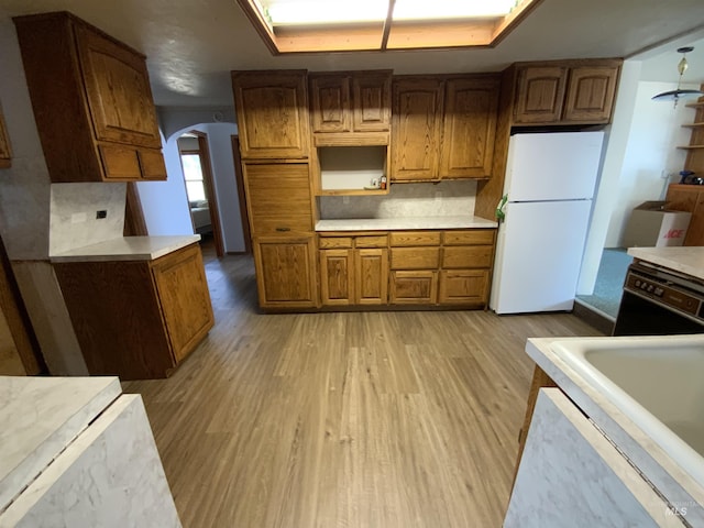 kitchen with black dishwasher, sink, backsplash, white fridge, and light hardwood / wood-style floors