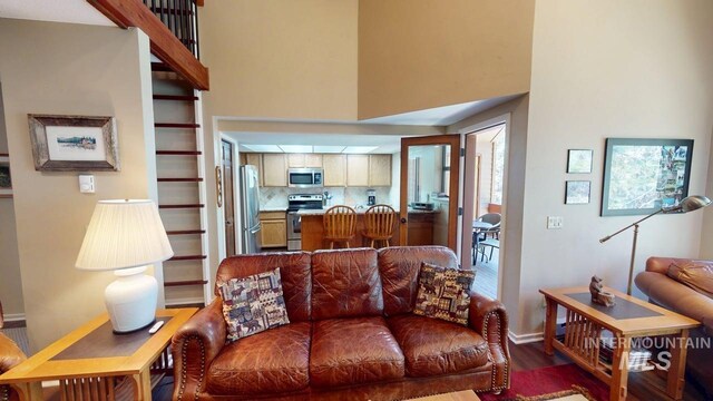 living area with baseboards, a high ceiling, and wood finished floors