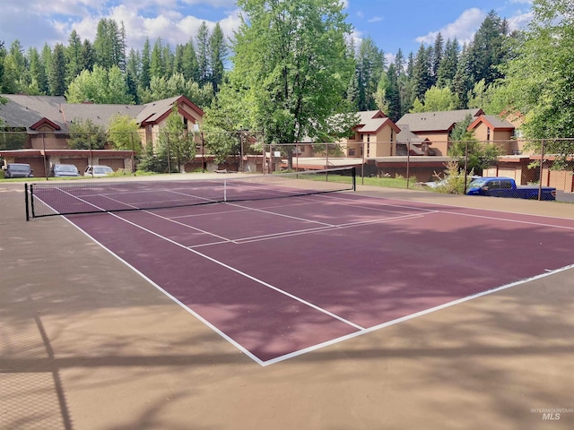 view of tennis court with community basketball court and fence