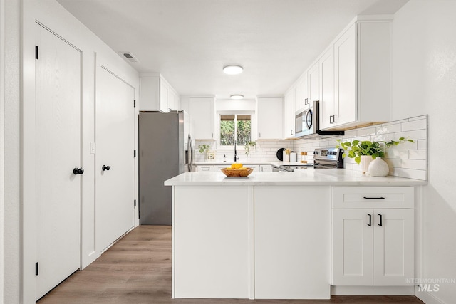 64 Borah, Nampa, ID 83651 - kitchen with stainless steel appliances, a peninsula, backsplash, light countertops, and white cabinets