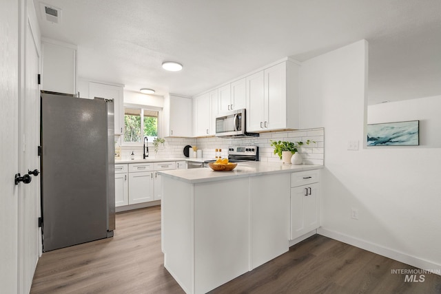 64 Borah, Nampa, ID 83651 - kitchen featuring appliances with stainless steel finishes, a peninsula, wood finished floors, tasteful backsplash, and light countertops