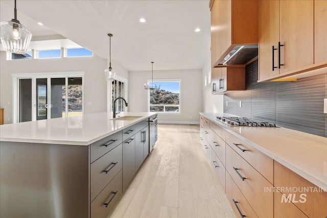 kitchen with stainless steel appliances, sink, hanging light fixtures, a large island, and gray cabinetry