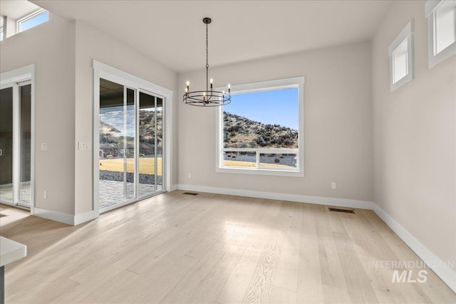 unfurnished dining area with a chandelier and light hardwood / wood-style flooring