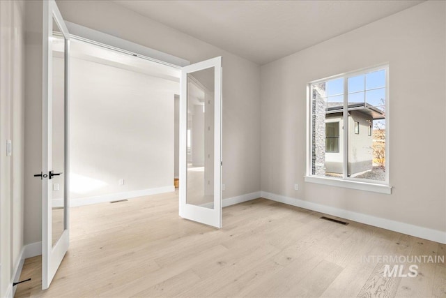 spare room featuring french doors and light hardwood / wood-style flooring