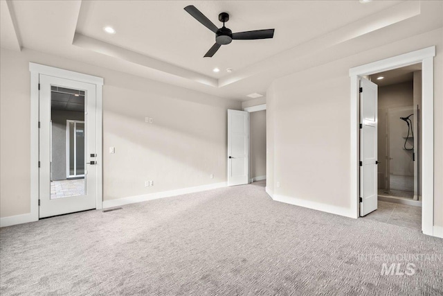 unfurnished bedroom with ceiling fan, light colored carpet, and a raised ceiling