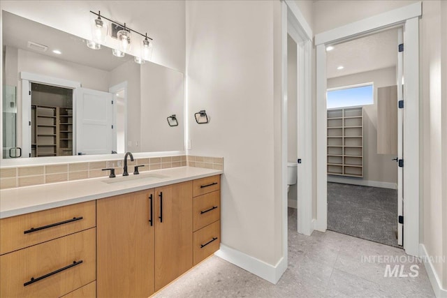 bathroom featuring toilet, backsplash, and vanity