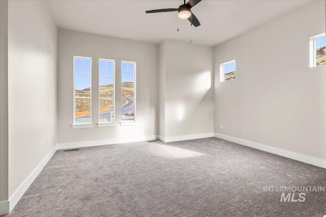 empty room with ceiling fan, plenty of natural light, and carpet floors