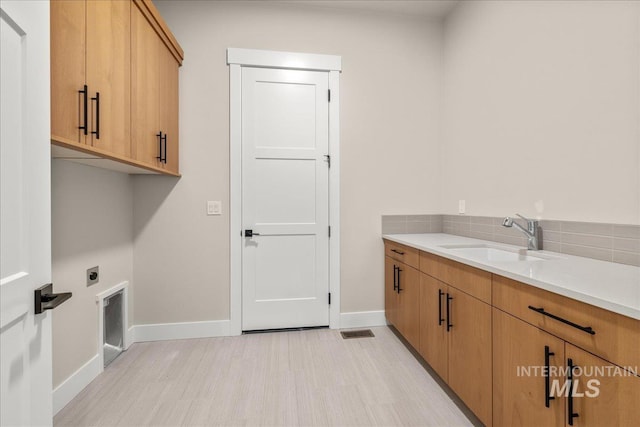 washroom featuring sink, electric dryer hookup, and cabinets