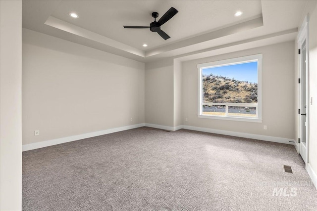 carpeted spare room featuring ceiling fan and a tray ceiling