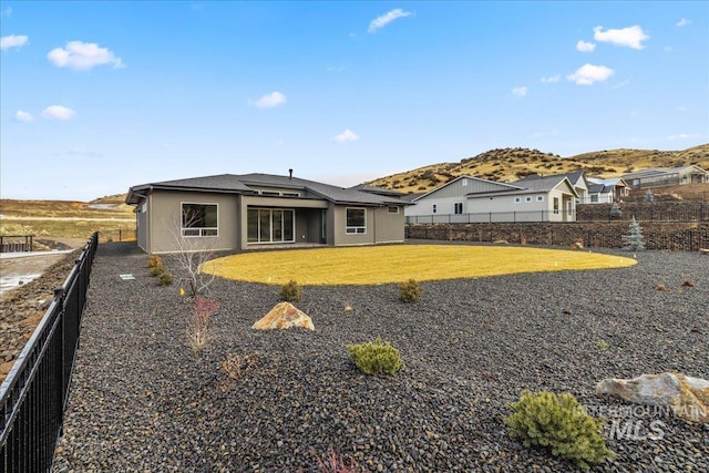 rear view of house with a mountain view and a yard