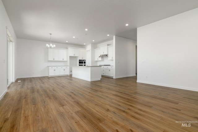 unfurnished living room featuring a notable chandelier and hardwood / wood-style flooring