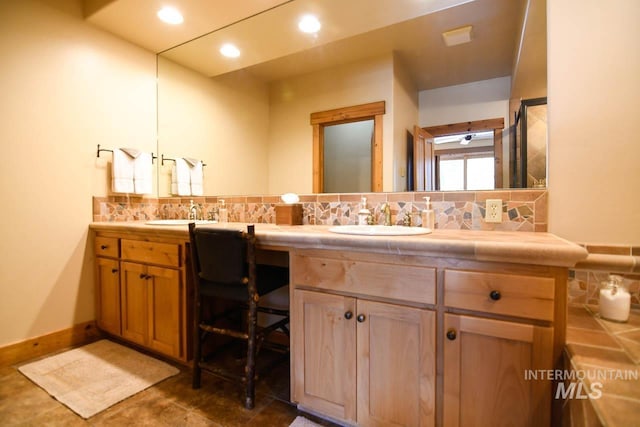 full bath with a sink, backsplash, and double vanity