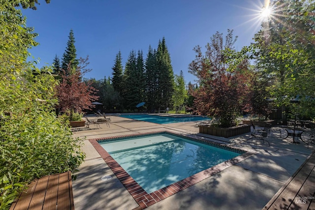 outdoor pool featuring a jacuzzi and a patio area
