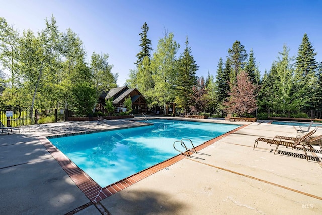 community pool featuring fence and a patio