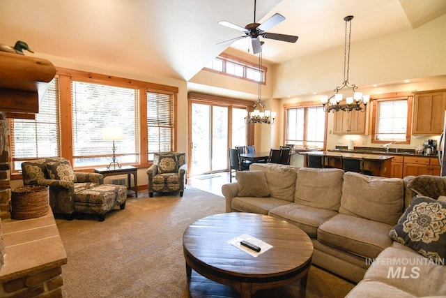 living area featuring carpet floors, ceiling fan with notable chandelier, and high vaulted ceiling