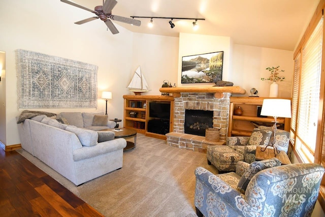 living room with rail lighting, vaulted ceiling, ceiling fan, and a fireplace