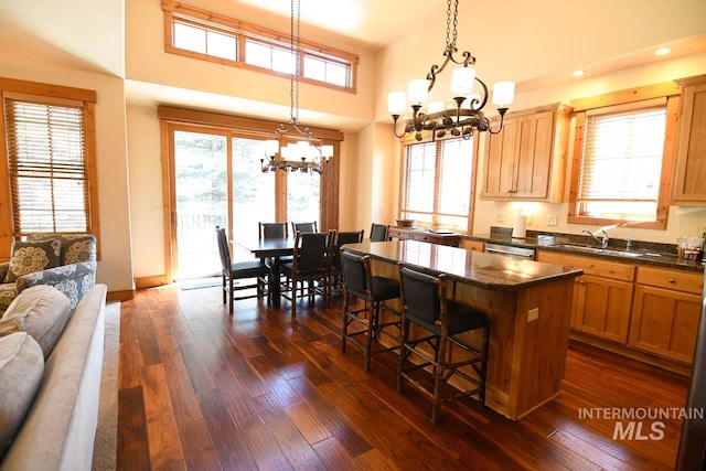 kitchen featuring a kitchen breakfast bar, a center island, stainless steel dishwasher, a sink, and an inviting chandelier