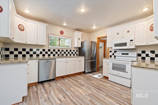 316 Maple Ave, Emmett, ID 83617 - kitchen featuring stainless steel appliances, a sink, backsplash, white cabinets, and light wood-style floors