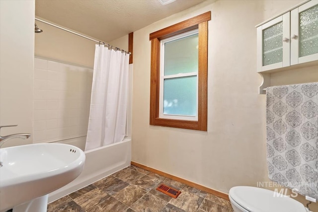 316 Maple Ave, Emmett, ID 83617 - full bath featuring toilet, baseboards, shower / bath combo with shower curtain, a sink, and stone finish floors