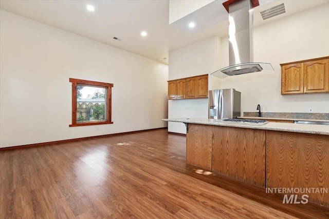 316 Maple Ave, Emmett, ID 83617 - kitchen featuring wall chimney range hood, a towering ceiling, appliances with stainless steel finishes, dark wood finished floors, and light stone countertops