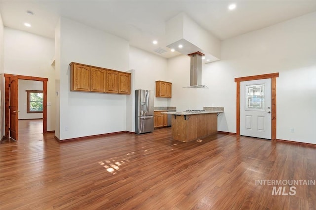 316 Maple Ave, Emmett, ID 83617 - kitchen featuring stainless steel refrigerator with ice dispenser, ventilation hood, a towering ceiling, a peninsula, and brown cabinetry