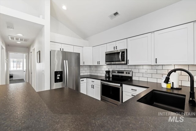 kitchen featuring a sink, stainless steel appliances, dark countertops, and visible vents