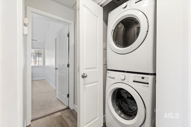 laundry room with light wood finished floors, laundry area, baseboards, and stacked washer and dryer