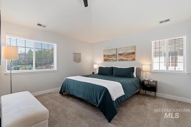 carpeted bedroom featuring visible vents, multiple windows, and baseboards