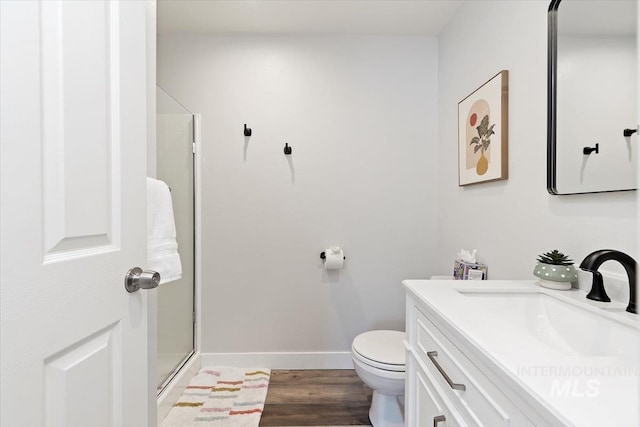 full bathroom featuring toilet, a stall shower, wood finished floors, baseboards, and vanity