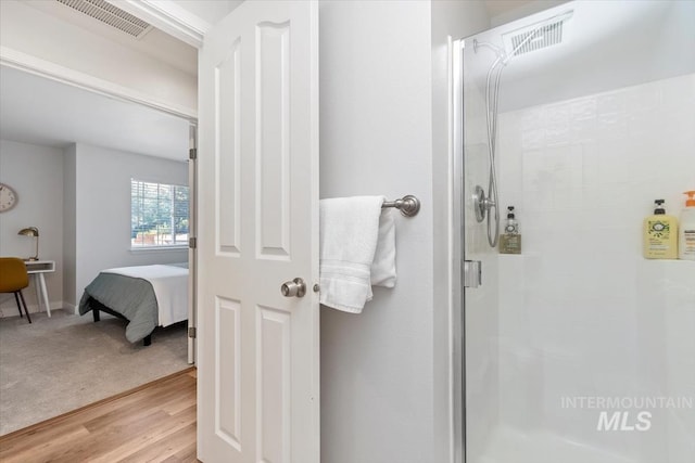 ensuite bathroom with visible vents, a stall shower, ensuite bath, and wood finished floors