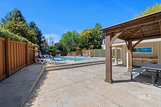 view of patio / terrace with a gazebo, a community pool, and a fenced backyard