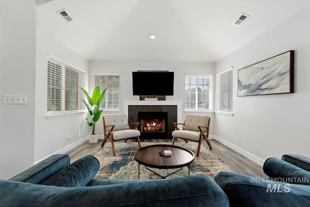 living area with wood finished floors, a fireplace, visible vents, and baseboards