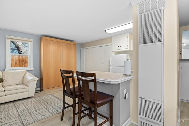 2517/2519 N 21st, Boise, ID 83702 - kitchen featuring light countertops, freestanding refrigerator, a breakfast bar area, white cabinetry, and light wood-style flooring