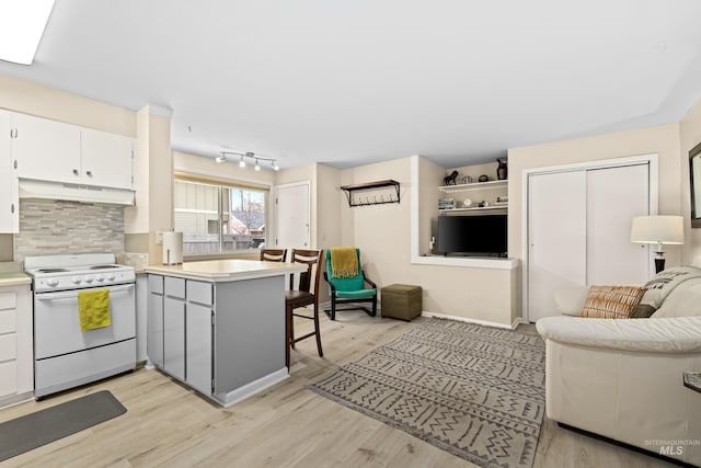 2517/2519 N 21st, Boise, ID 83702 - kitchen with open floor plan, white electric range oven, under cabinet range hood, backsplash, and a peninsula