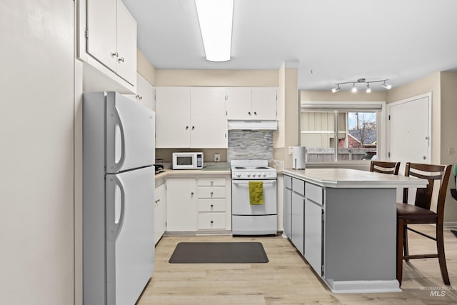 2517/2519 N 21st, Boise, ID 83702 - kitchen with a peninsula, light wood finished floors, white appliances, under cabinet range hood, and backsplash