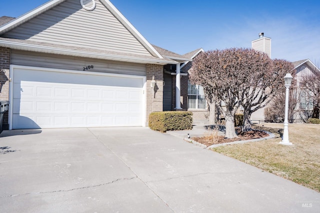 ranch-style house featuring concrete driveway, an attached garage, a shingled roof, brick siding, and a chimney