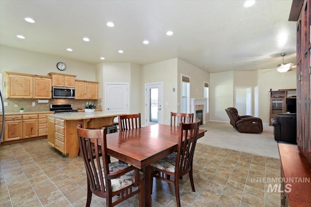 carpeted dining area with ceiling fan