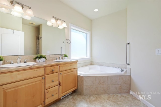 bathroom featuring vanity and tiled bath