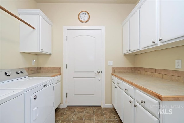 washroom with washing machine and clothes dryer, cabinets, and dark tile patterned flooring