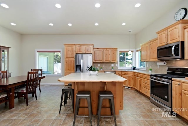 kitchen with a center island, a kitchen breakfast bar, sink, appliances with stainless steel finishes, and tasteful backsplash