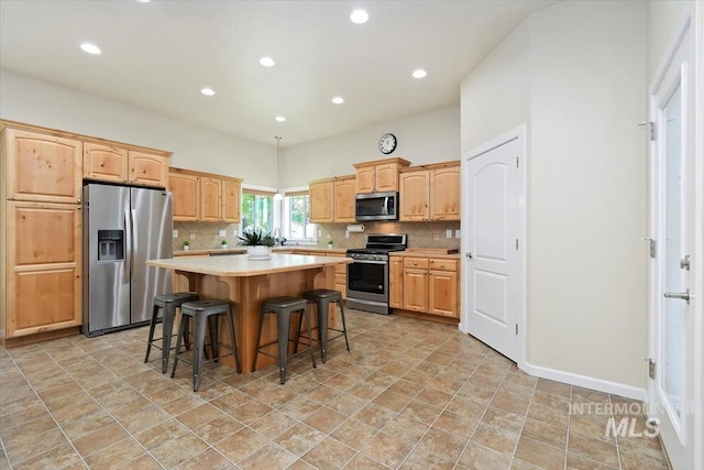 kitchen with backsplash, a kitchen island, a breakfast bar area, and appliances with stainless steel finishes